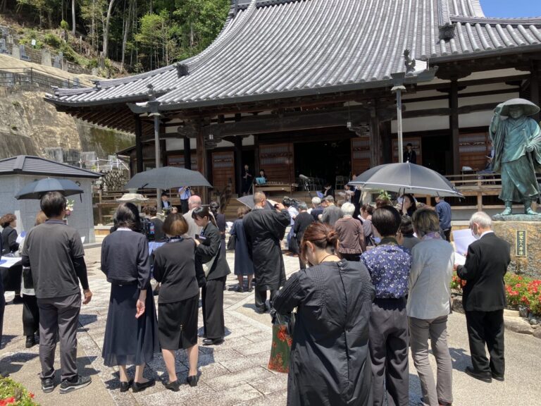 日傘をさして教蓮寺の境内に集まる参列者